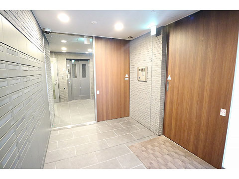 エントランス グレー系のタイルに木目調の自動ドアで落ち着いた